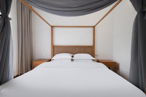 a bedroom with a large white bed with black drapes at 青城山喜遇安下私汤民宿 in Dujiangyan
