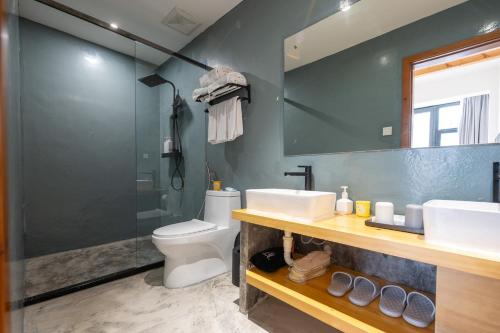 a bathroom with a sink and a toilet and a shower at 青城山喜遇安下私汤民宿 in Dujiangyan