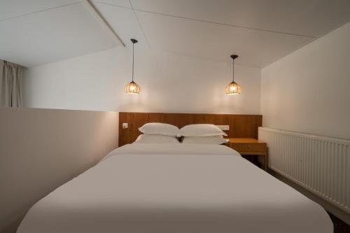 a bedroom with a large white bed with two pillows at 青城山喜遇安下私汤民宿 in Dujiangyan