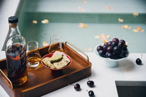 a tray with a bottle of alcohol and a bowl of grapes at 青城山喜遇安下私汤民宿 in Dujiangyan