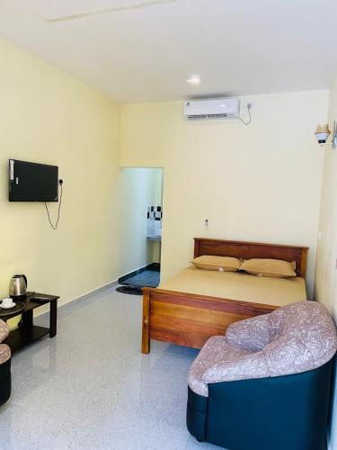 a bedroom with a bed and a couch and a tv at Great Victoria Palace in Ratnapura