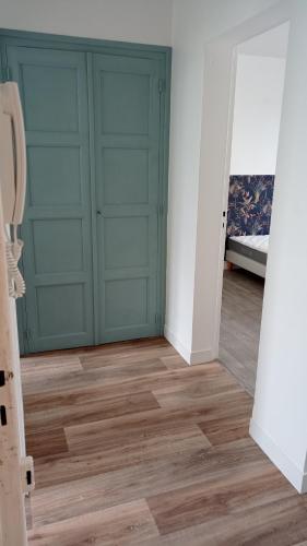 une pièce avec deux portes vertes et un plancher en bois dans l'établissement Appartement rénové hypercentre plage à 5 minutes à pied, à Saint-Nazaire