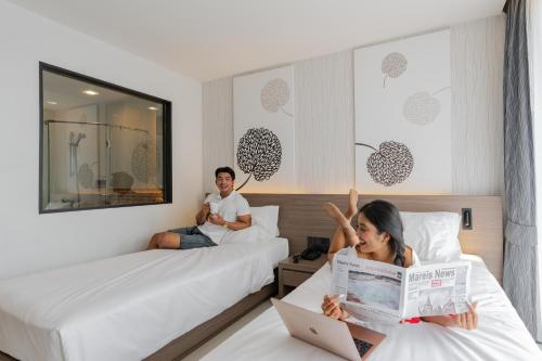 a man and woman sitting on beds in a hotel room at Citrus Patong Hotel by Compass Hospitality in Patong Beach