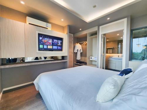 a bedroom with a white bed and a tv at Bayphere Hotel Pattaya JC in Na Jomtien