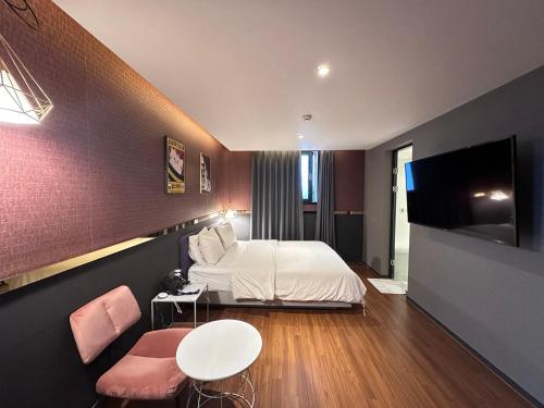 a bedroom with a bed and a table and a tv at Browndot Pohang Jukdo in Pohang