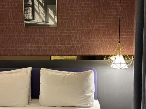 a bed with two white pillows and a hanging light at Browndot Pohang Jukdo in Pohang