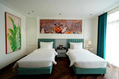 two beds in a room with a painting on the wall at Belliss Hotel And Spa Dai Lai in Phúc Yên
