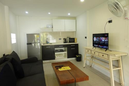 a living room with a couch and a table with a television at Aussieland Bungalows in Lamai