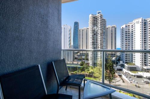 a balcony with two chairs and a view of a city at Legends Resort 9th Floor Ocean Views - CoastHM in Gold Coast