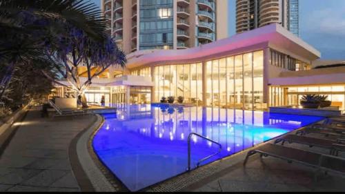 a large building with a swimming pool at night at Legends Resort 9th Floor Ocean Views - CoastHM in Gold Coast