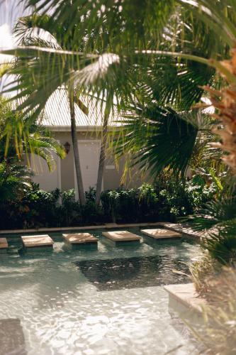 a swimming pool with chaise lounges and palm trees at Sugar Beach Mauritius in Flic-en-Flac