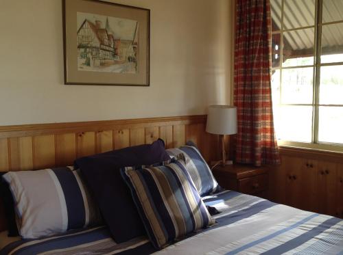 a bedroom with a bed with pillows and a window at Fergies Hill Spa Cottage @ Granite Ridge Wines in Ballandean