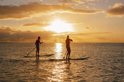 two people on paddle boards in the ocean at sunset at Sugar Beach Mauritius in Flic-en-Flac