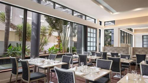 a restaurant with tables and chairs and large windows at Comfortable Hotel Studio at Legends Resort - CoastHM in Gold Coast