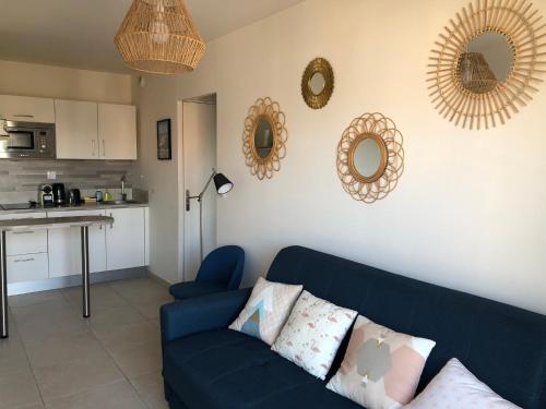 - un salon avec un canapé bleu et des miroirs sur le mur dans l'établissement Le petit navire - accès direct plage, à Cabourg