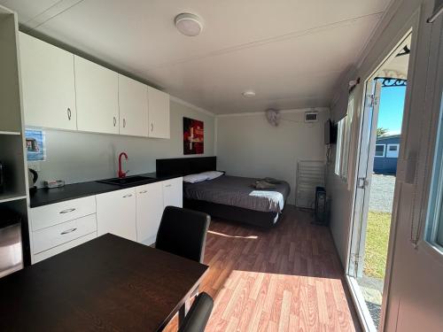 a kitchen and a bedroom with a bed in a trailer at Westshore Holiday Park in Napier