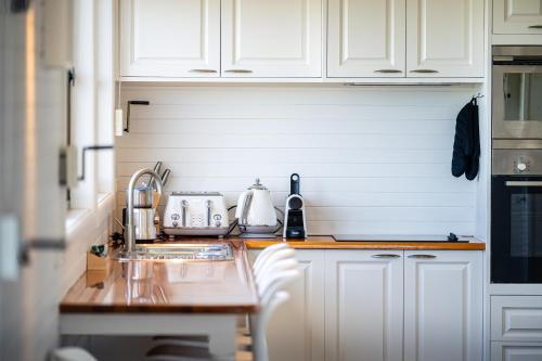 a kitchen with white cabinets and a sink at Nine Mile House in Swansea