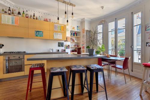 - une cuisine avec un comptoir et des tabourets dans l'établissement Appartement Poliveau - Welkeys, à Paris