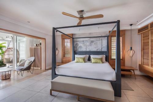 a bedroom with a four poster bed and a living room at Sugar Beach Mauritius in Flic-en-Flac