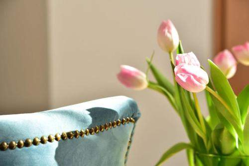 a vase of pink tulips next to a blue chair at Hotel Meereseck in Bansin