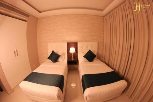 two beds in a small room with a lamp at Dancenter Jewel Near World Trade Center in Manama