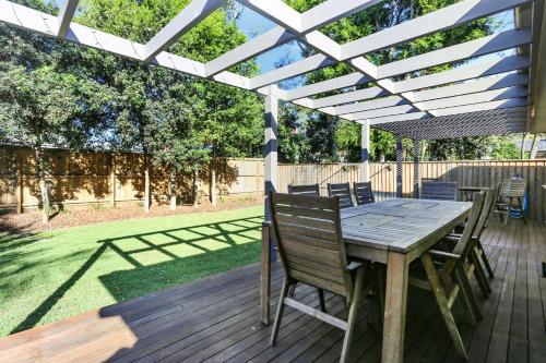 a wooden deck with a table and chairs under a pergola at Vitamin Sea Pet Friendly in Hawks Nest