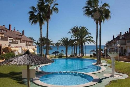 a swimming pool with palm trees and the ocean at Casa primera línea vistas al mar con Parking in La Venteta