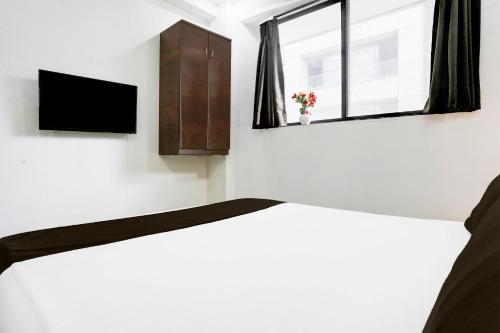 a bedroom with a bed and a window at Super Hotel O VIP Road formerly Hotel Lotus in Surat