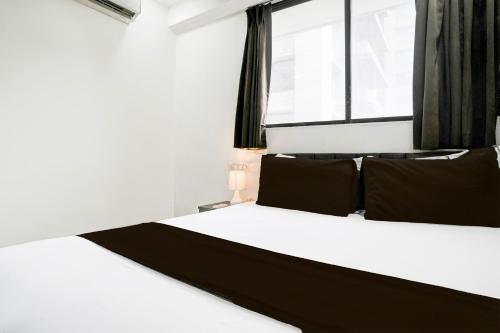 a bedroom with a white bed with black pillows and a window at Super Hotel O VIP Road formerly Hotel Lotus in Surat