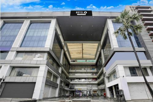 an office building with a palm tree in front of it at Super Hotel O VIP Road formerly Hotel Lotus in Surat