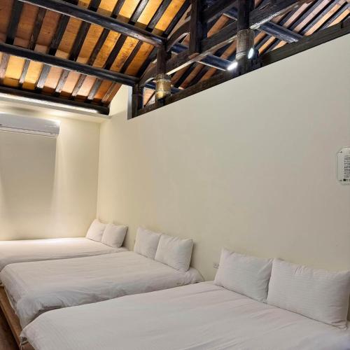 two beds in a room with wooden ceilings at 老宅拾光Lao Shih Kuang-預訂後聯繫才會保留 in Tainan