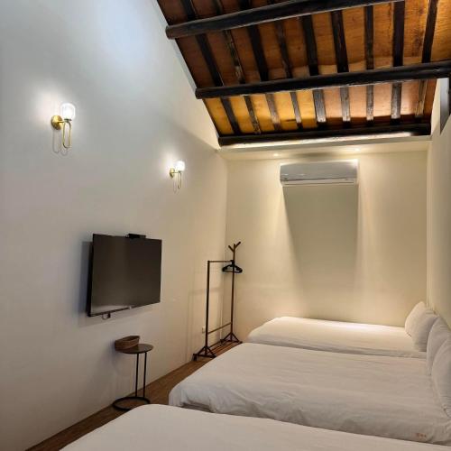 a bedroom with two beds and a flat screen tv at 老宅拾光Lao Shih Kuang-預訂後聯繫才會保留 in Tainan