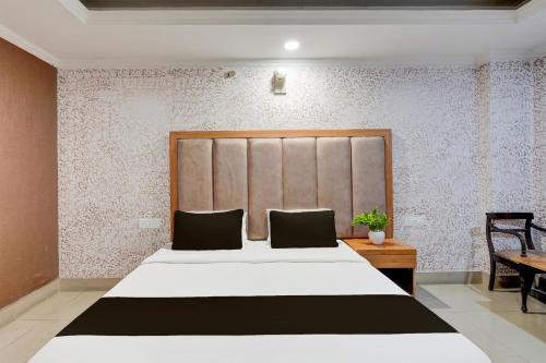 a bedroom with a large white bed and a desk at Super Collection O Awas Vikas Near Bus Stand Formerly Hotel Rivera in Rudrapur