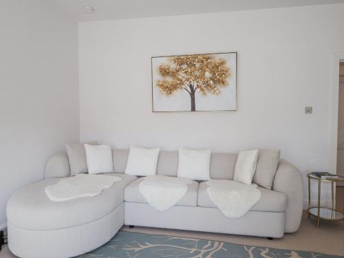 a white couch in a living room with a tree on the wall at Aspen Spa Apartment in Dornoch