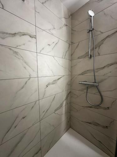 a shower with white marble walls in a bathroom at L'écrin du Lac St-Point in Malbuisson