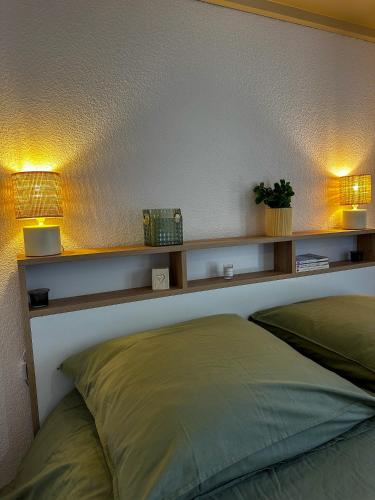 a bedroom with two lights on the wall and a bed at L'écrin du Lac St-Point in Malbuisson
