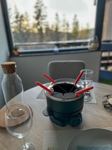a table with a pot on a table with wine glasses at L'écrin du Lac St-Point in Malbuisson