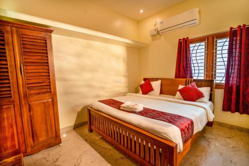 a bedroom with a large bed with red pillows at Bairava Bliss Inn - Rameswaram in Rāmeswaram