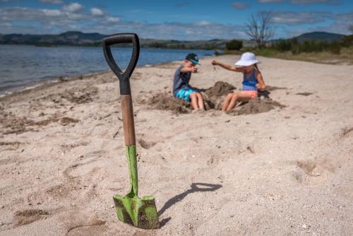 a stick in the sand with two people on a beach at Cosy Cottage Thermal Holiday Park in Rotorua