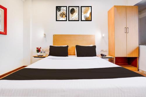 a bedroom with a large white bed with a wooden headboard at The Unicontinental in Mumbai