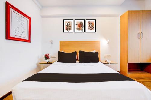 a bedroom with a large white bed with black pillows at The Unicontinental in Mumbai