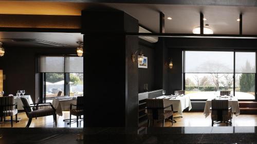 a dining room with tables and chairs and windows at the salon 伊豆高原 Hotels & Resort in Ito