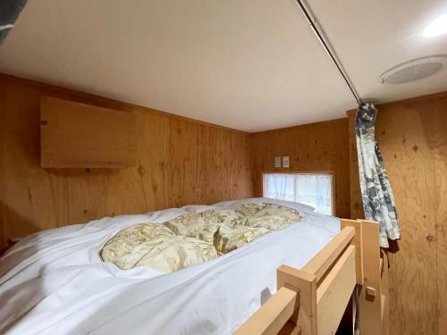a bed in a room with wooden walls at Guesthouse Wanokaze mix domitory / Vacation STAY 32202 in Otaru