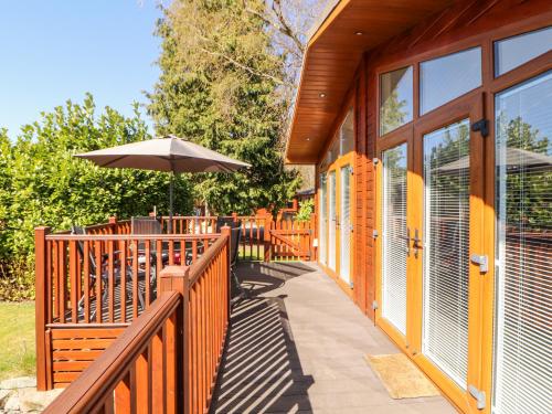 a wooden deck with an umbrella on a building at Bowness 66 in Windermere