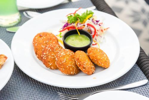 a plate of food with onion rings and a salad at DLS Divine River Resort and Spa, Rishikesh in Rishīkesh