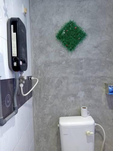 a bathroom with a toilet and a phone on the wall at The 1975 Hotel Empire in Kuantan