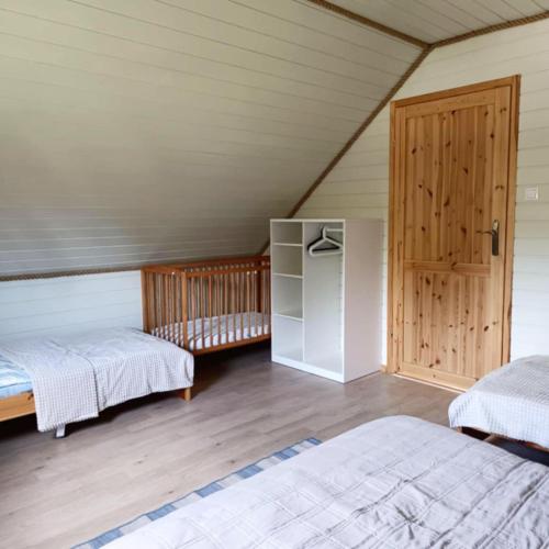 a attic bedroom with two beds and a wooden door at Ogrzewane Domki u Kamili Sztutowo, Jacuzzi, plac zabaw, klimatyzacja, parking# 884#90#09#01 in Sztutowo