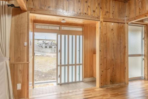 a room with wooden walls and a large window at たーちやー in Motobu
