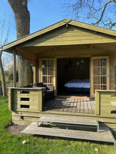 a wooden cabin with a bed on a deck at Lodge op Recreatiepark de Uilenburg in Hommerts