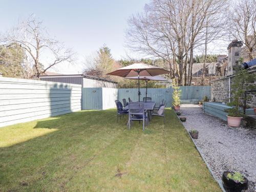 a table and chairs under an umbrella in a backyard at Glenspey in Kingussie